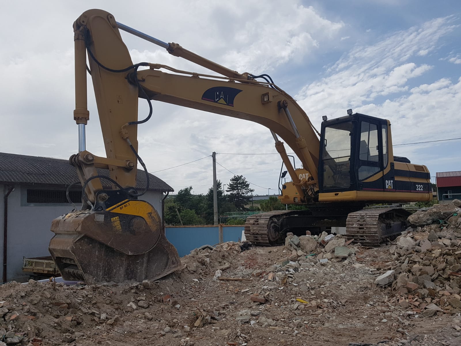 Benna frantumatrice al lavoro sulle macerie per il recupero dei materiali